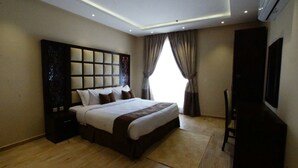 A modern hotel room with a large bed, a TV, and a window with curtains.