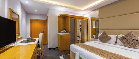 Una habitación de hotel con una cama, un escritorio, un televisor y un armario.