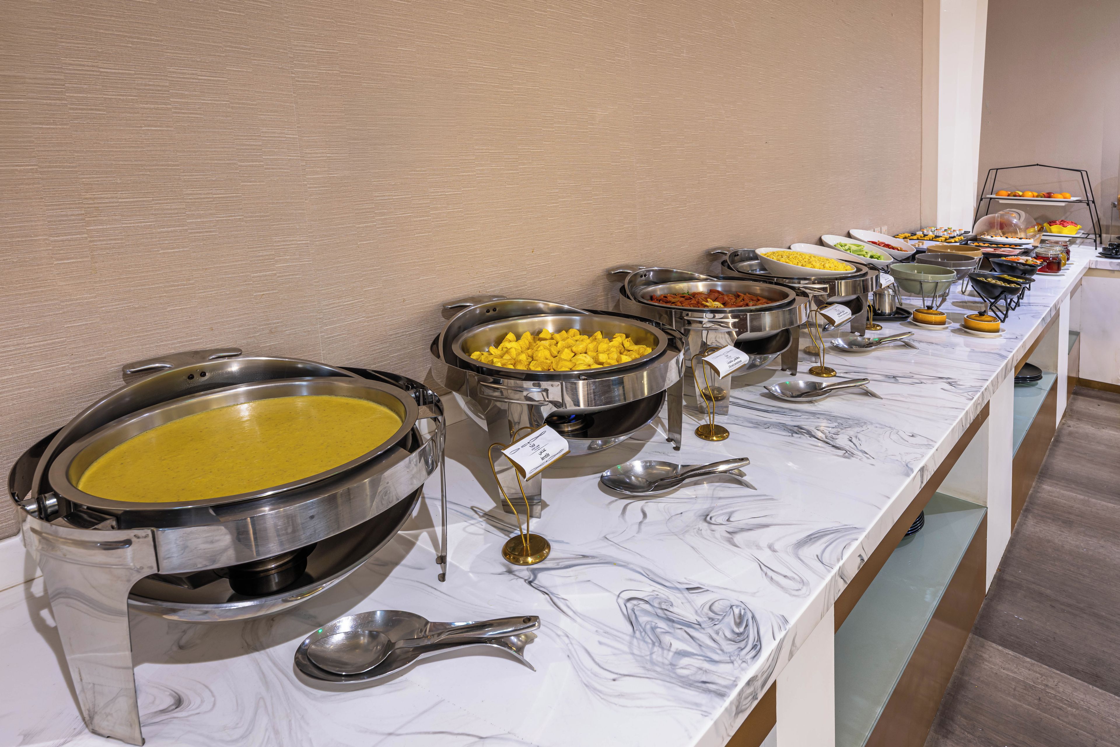 Una barra de buffet con diversos alimentos y utensilios.