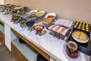 A buffet with various food items and condiments.
