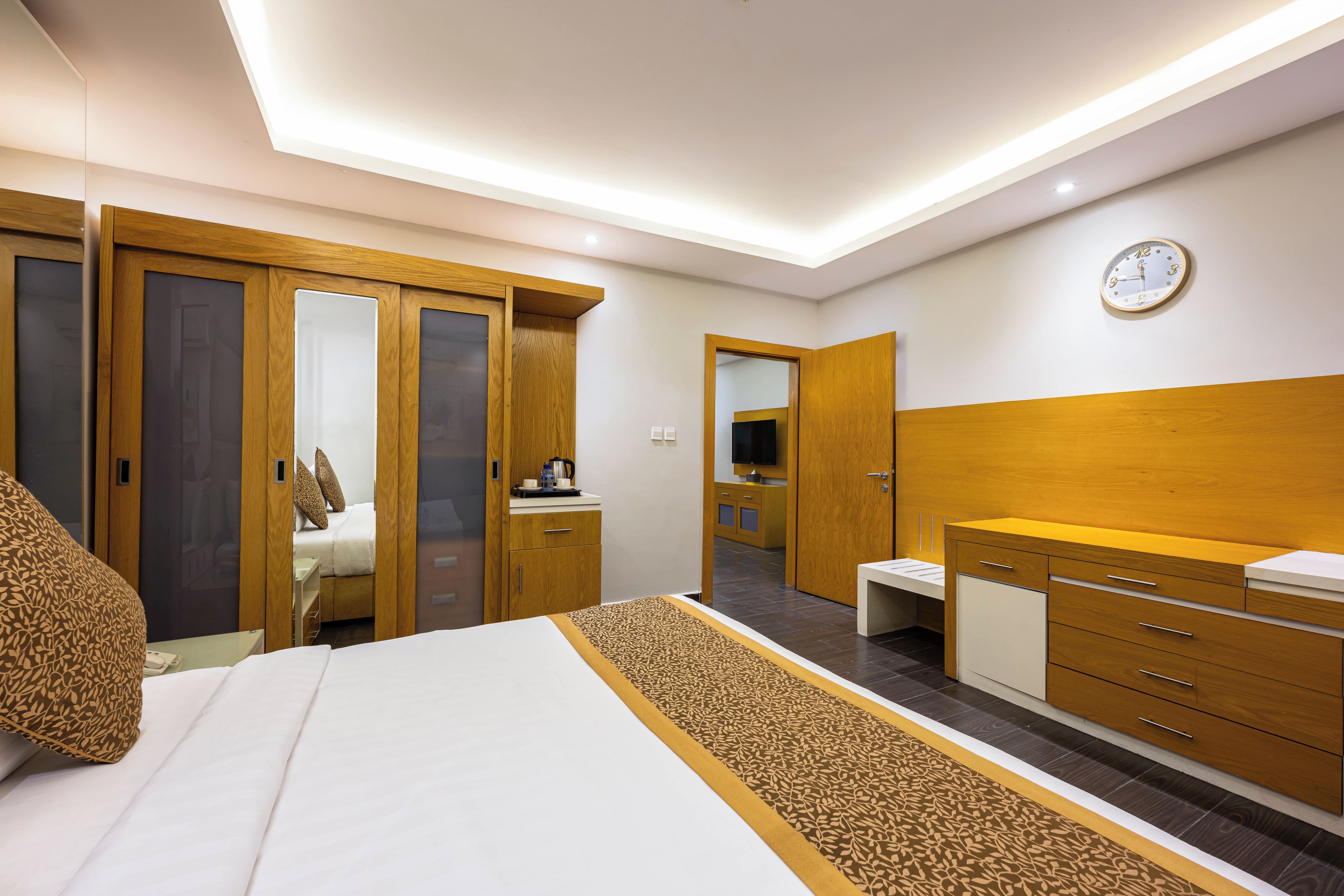 A modern bedroom with a bed, wardrobe, bedside table, and a mirror.