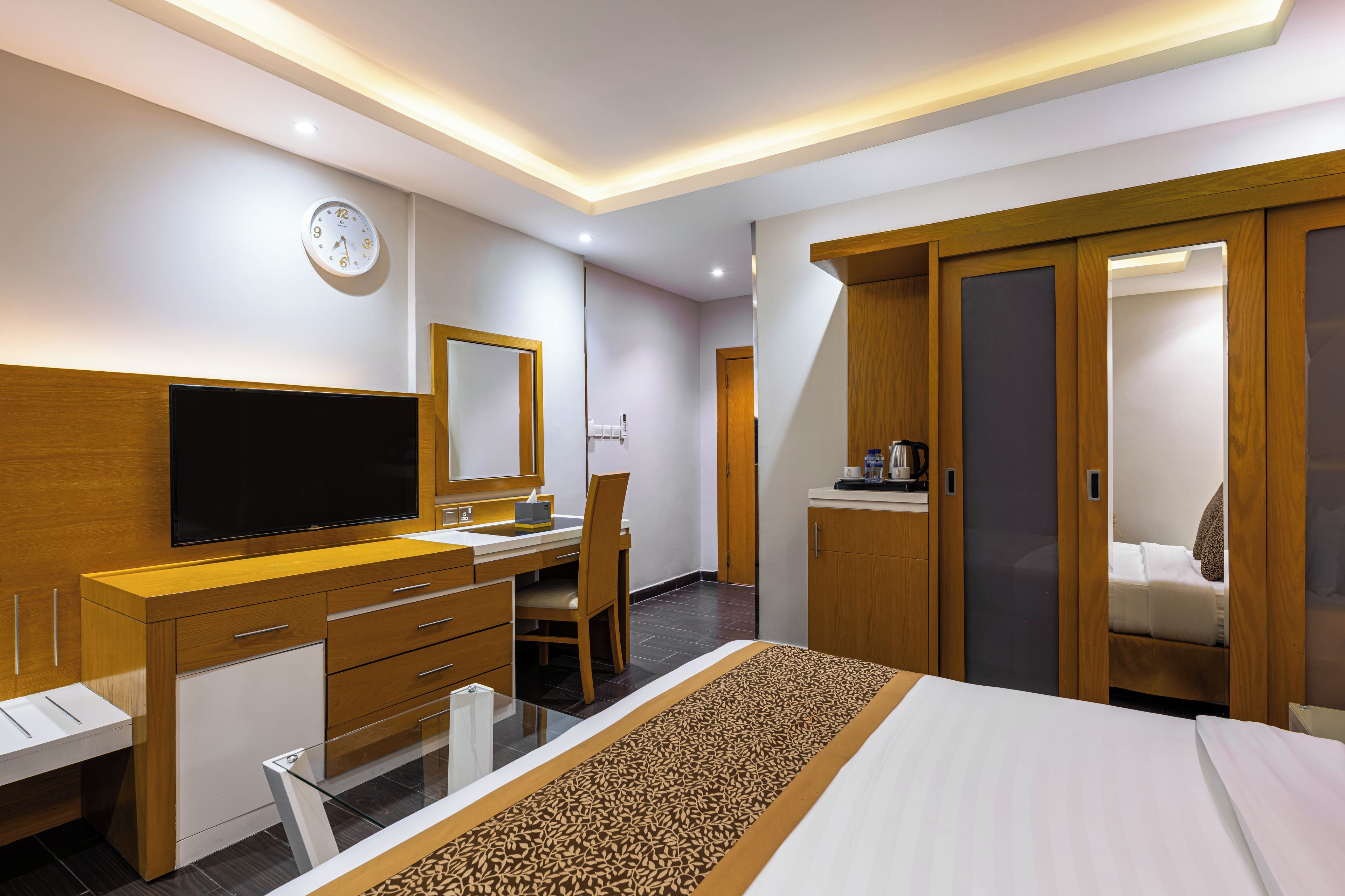 Habitació d'hotel amb un llit, una taula de nit amb televisió de pantalla plana, un armari i una porta al bany.