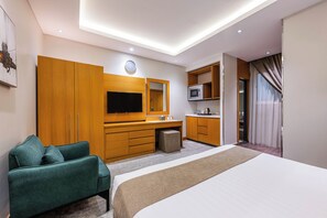Quarto de hotel moderno com uma cama grande, televisão, micro-ondas e área de estar.