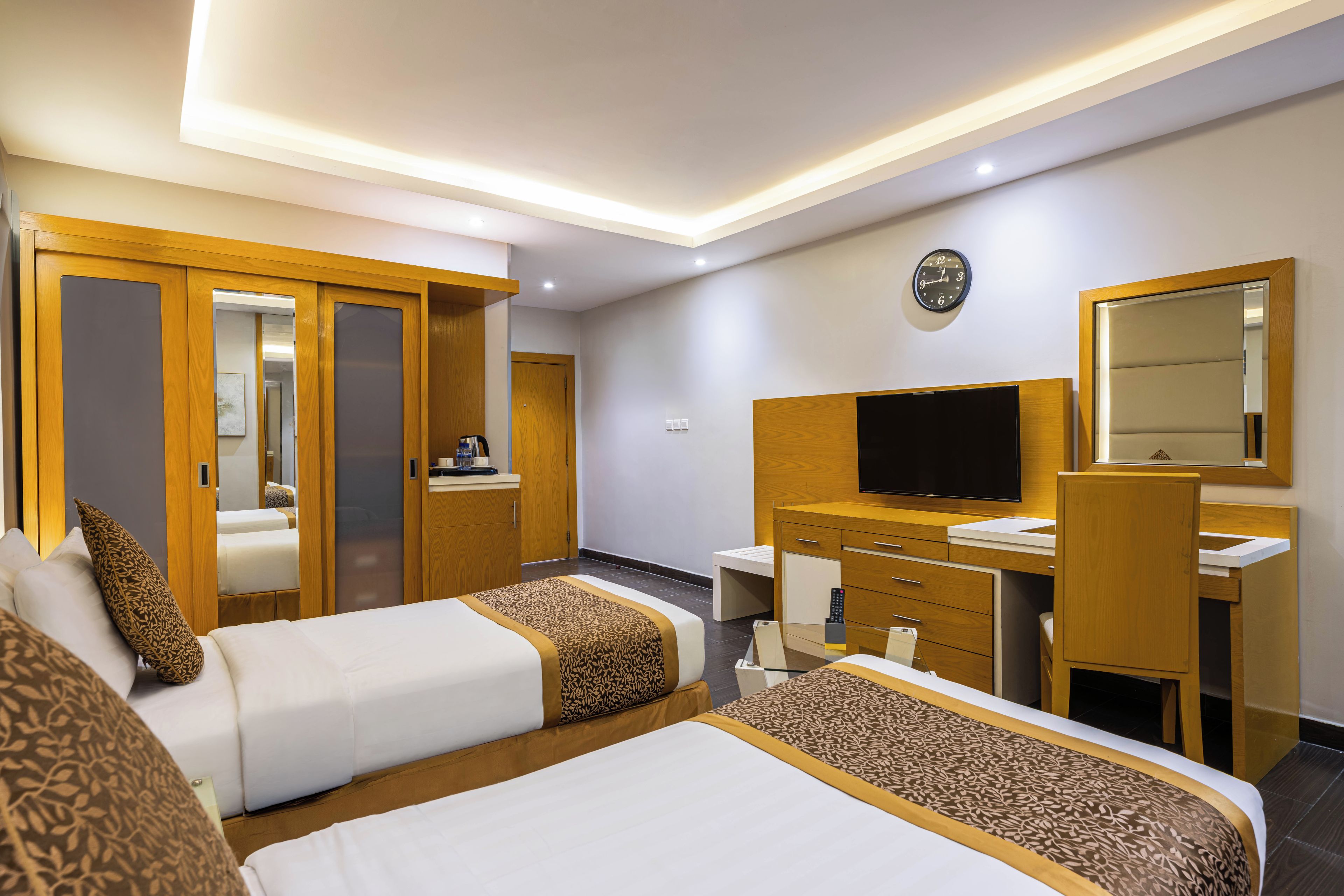 Habitación de hotel con dos camas, un escritorio, un televisor y un espejo.