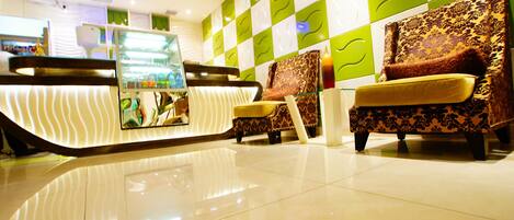 A modern hotel lobby with a reception desk, seating area, and decorative wall panels.