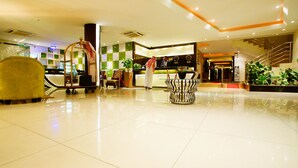 A hotel lobby with a reception desk, a seating area with a patterned table, and a luggage cart. - Sama Al Qasr Khorais - Economic (Riyadh)