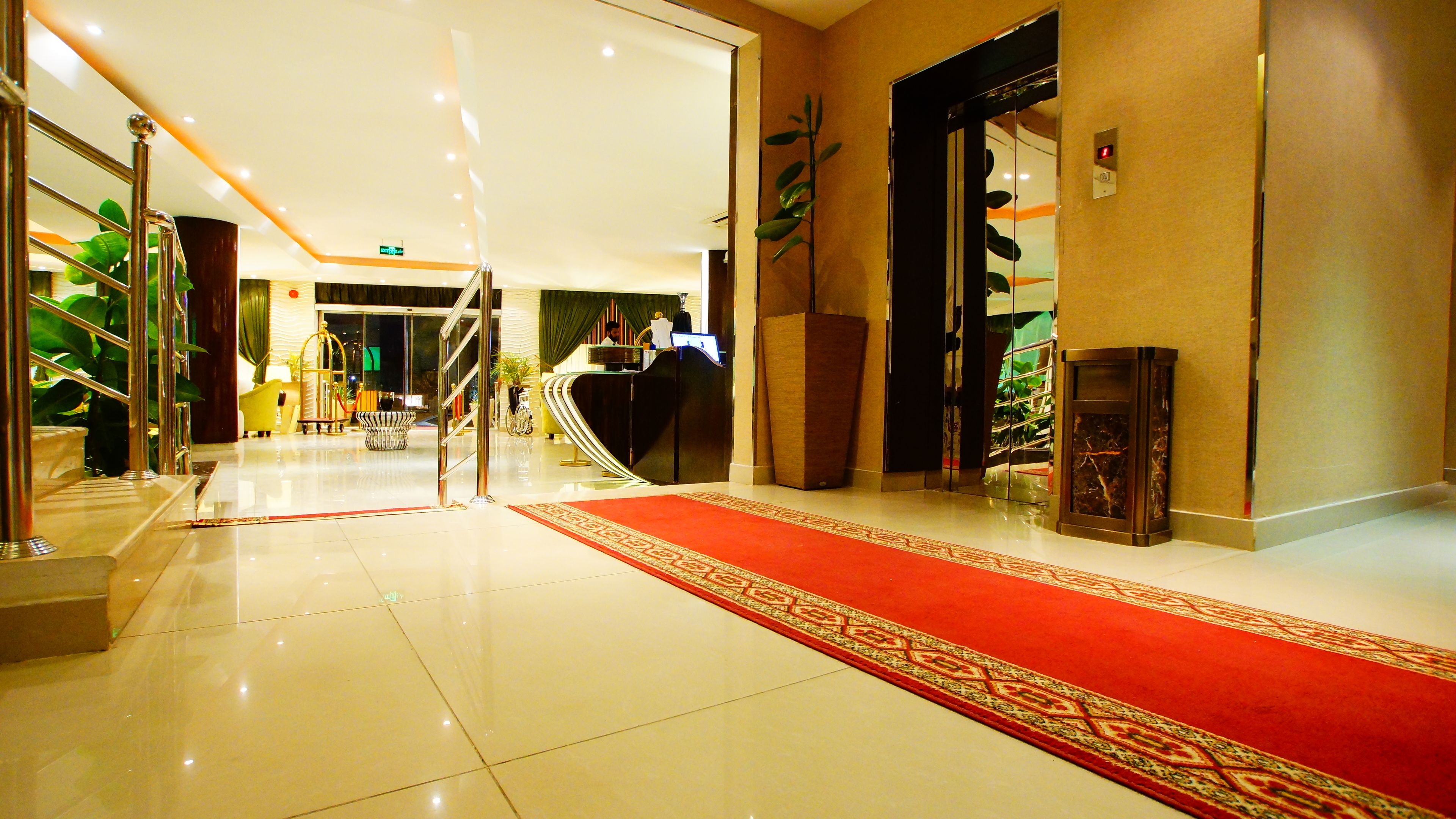 A hotel lobby with a red carpet, a reception desk, and a staircase.