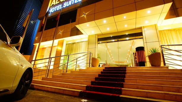 A hotel entrance with a staircase leading up to the door, a car parked in front, and a large potted plant on the steps. - Sama Al Qasr Khorais - Economic (Riyadh)