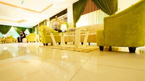 A spacious lobby with a polished floor, a seating area with yellow armchairs, a glass coffee table, and a decorative lamp. - Sama Al Qasr Khorais - Economic (Riyadh)