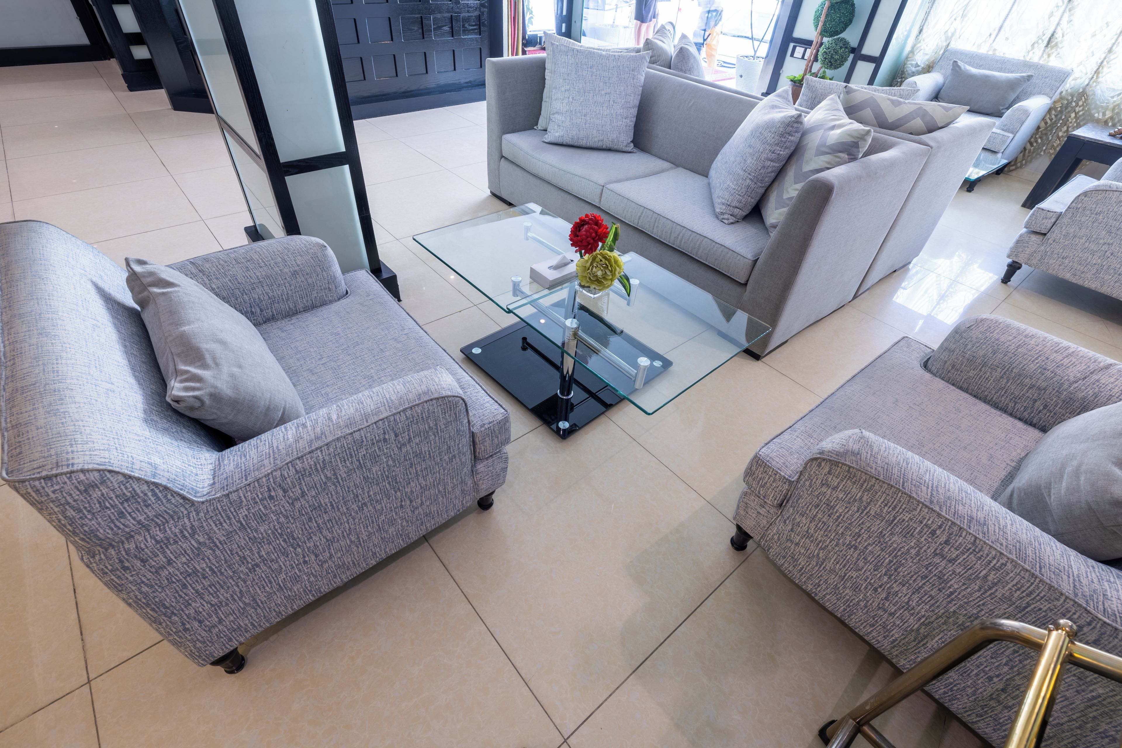 Ein modernes Wohnzimmer mit grauen Sofas, einem Glastisch und einer Vase mit Blumen.