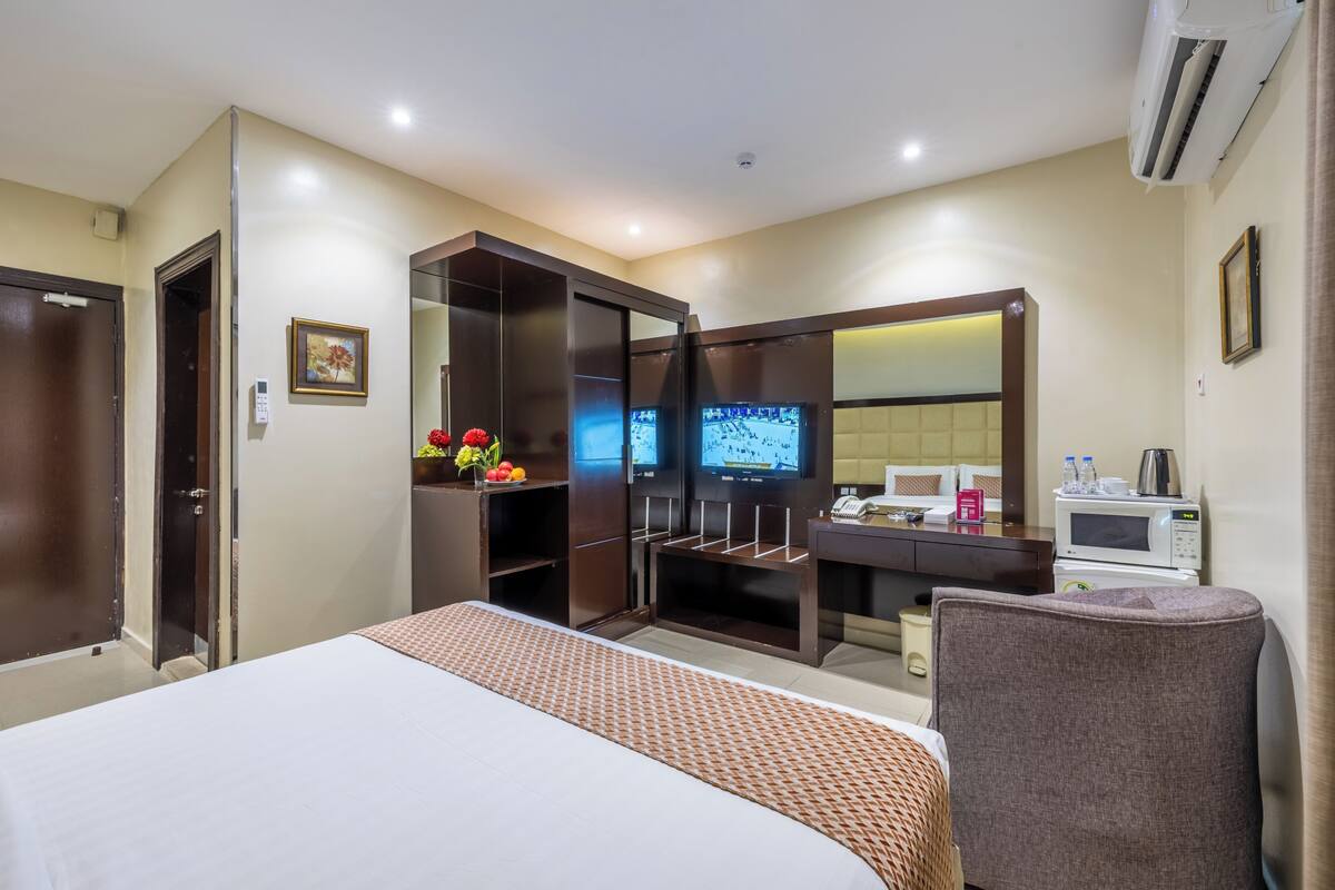 A hotel room with a bed, a TV, a microwave, a desk, and a wardrobe.