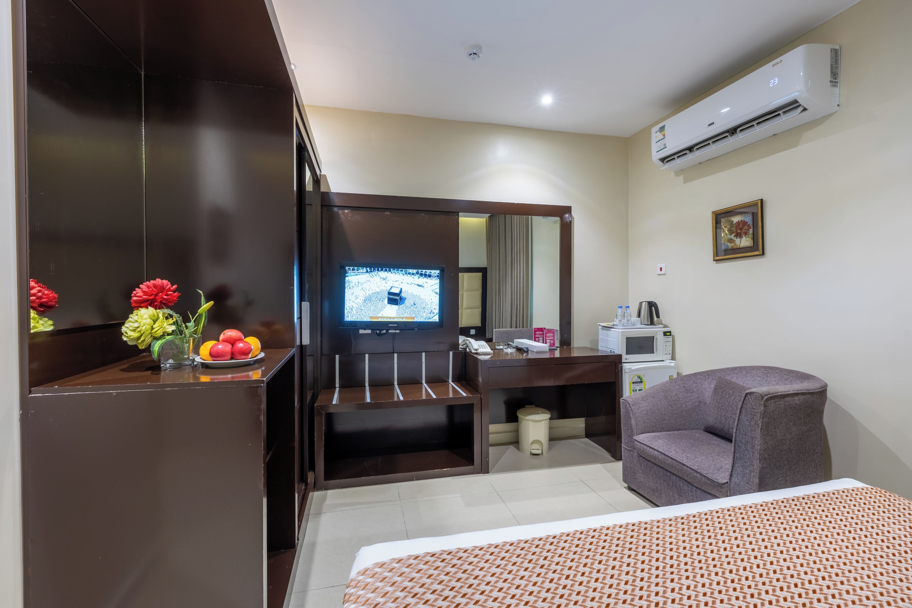 Habitación de hotel con cama, escritorio con computadora, silla, televisor y aire acondicionado.