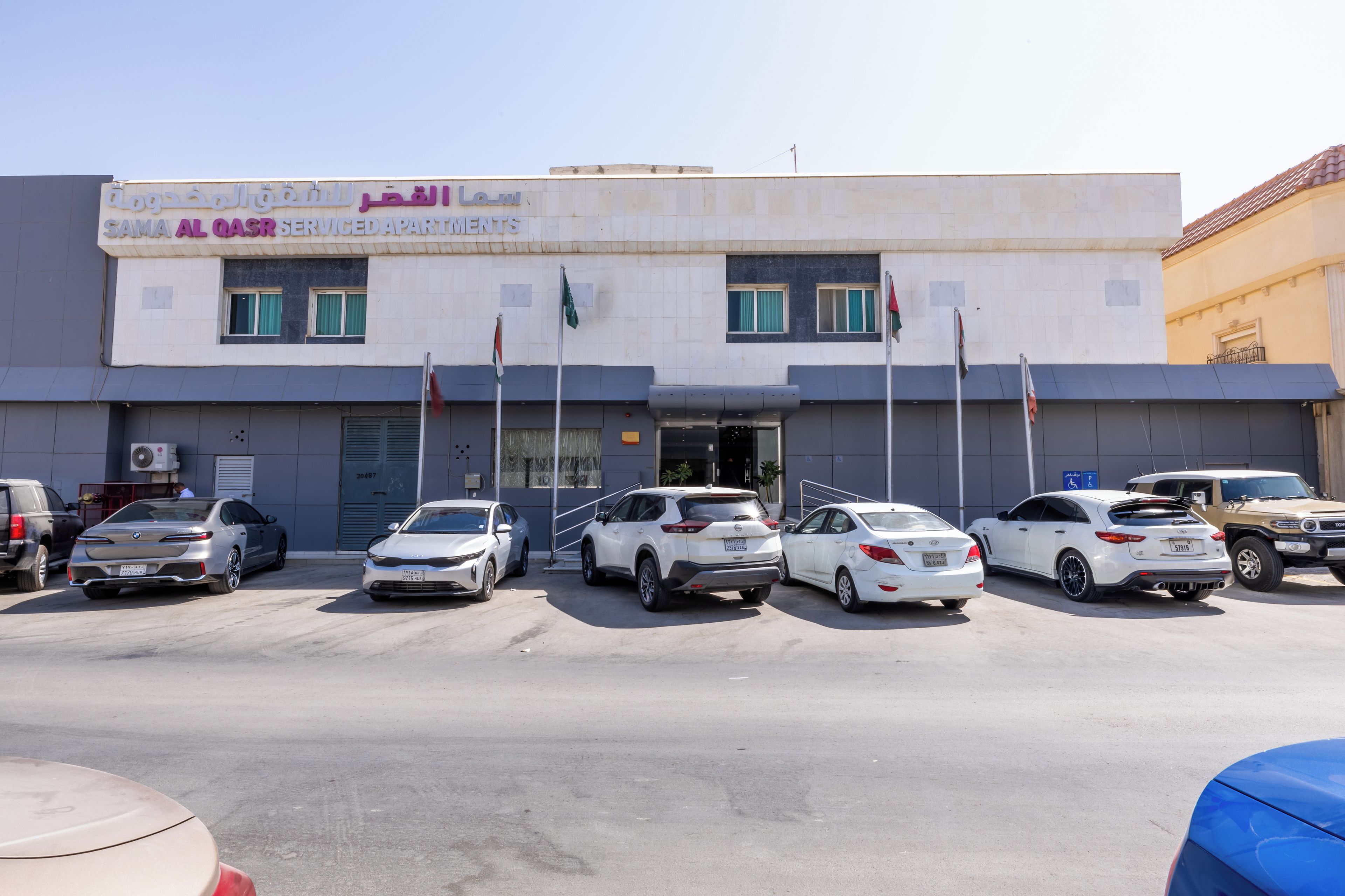 Un edificio con un cartello che indica una residenza con servizi. Diverse auto sono parcheggiate davanti.