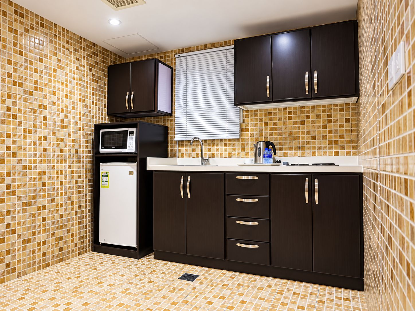 A compact kitchen with a microwave, refrigerator, and dark cabinets.