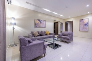 A modern living room with a sofa set, a glass coffee table, and two paintings on the wall. - Sama Al Qasr Al Muhammadiah - Economic (Riyadh)