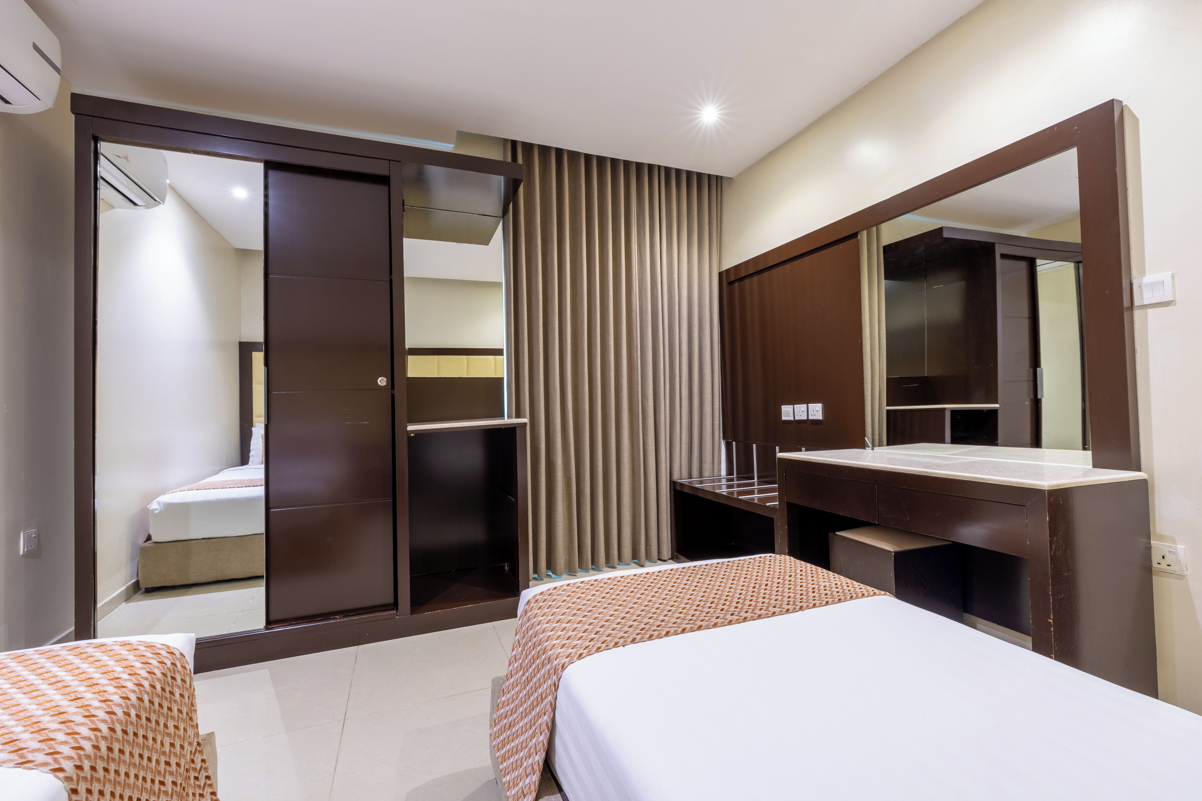 A hotel room with a bed, a wardrobe, a mirror, and a bathroom.