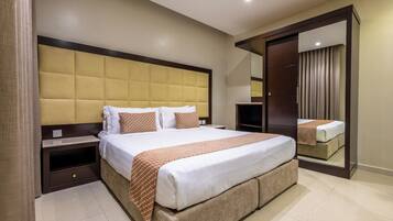 Habitación de hotel con una cama grande, un armario, una mesita de noche y un espejo.