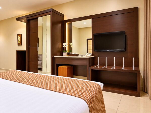 A hotel room with a large bed, a TV mounted on the wall, a desk with a telephone, and a mirror.