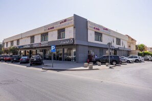 A multi-story building with commercial spaces on the ground floor, including a parking sign and storefronts. - Sama Al Qasr Al Muhammadiah - Economic (Riyadh)