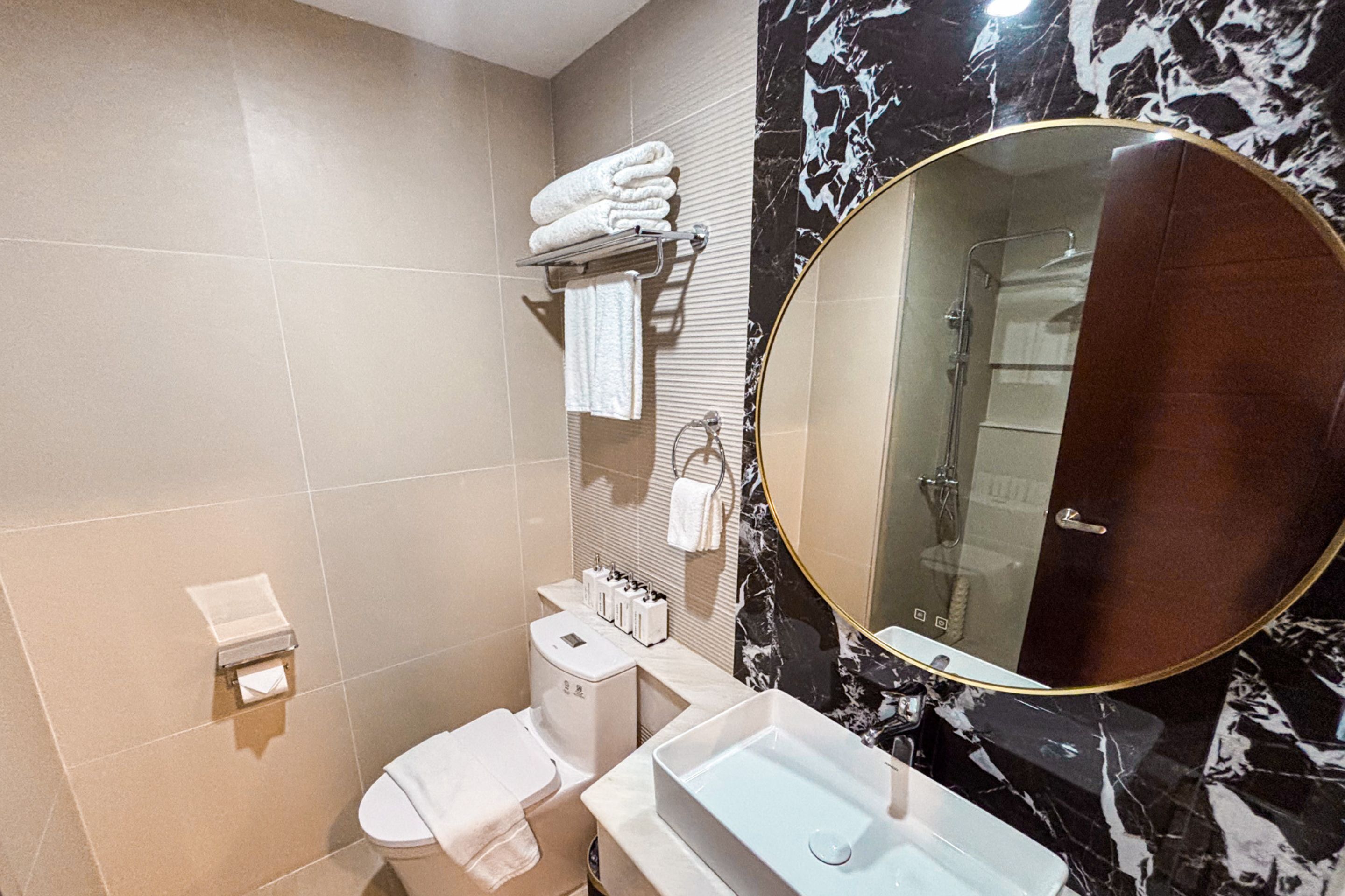 Een badkamer met toilet, wastafel en een grote spiegel.