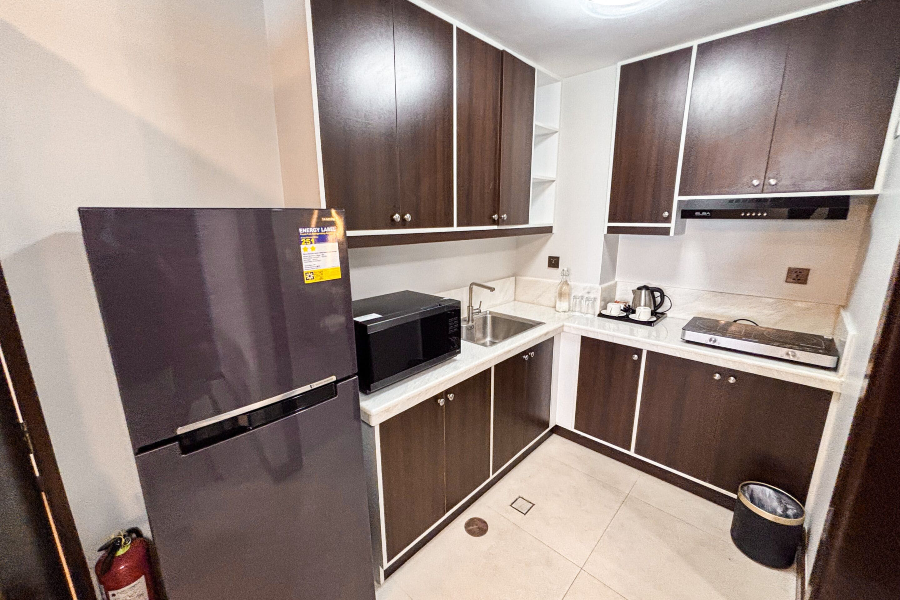 A compact kitchen with a refrigerator, microwave, sink, and a coffee maker.