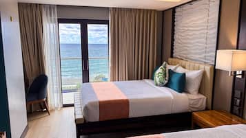 A hotel room with a bed, a desk, a chair, and a view of the ocean.