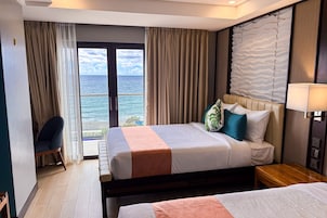 Una habitación de hotel con cama, escritorio, silla y vistas al océano.