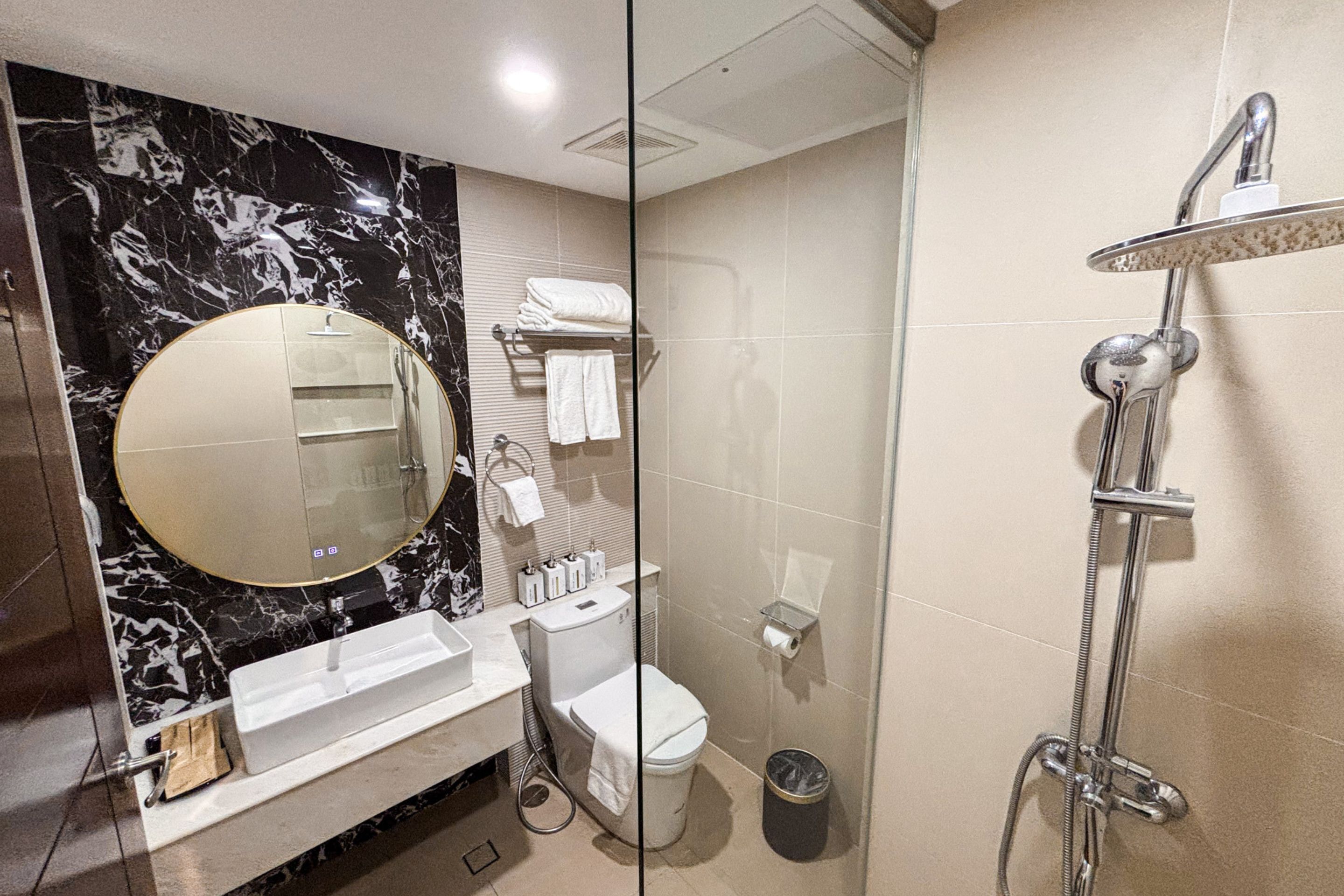 A bathroom with a marble vanity, a toilet, a shower, and a glass partition.