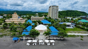 A hotel with multiple buildings, a large central structure, and a beach area with umbrellas and lounge chairs.