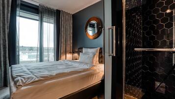 Un hotel moderno con una cama grande, un espejo redondo y vistas de la ciudad a través de la ventana.