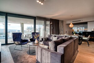 Una sala de estar moderna con un sofá seccional grande, un sillón azul y un comedor con una mesa y sillas.