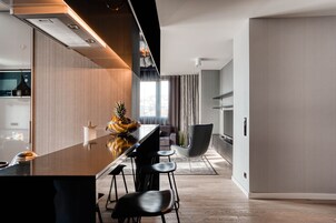 Una cocina moderna con una isla central, taburetes de bar y un comedor con una silla.