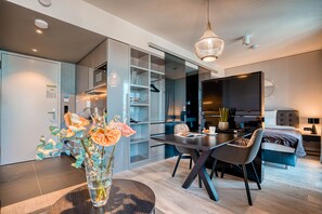 A modern hotel room with a dining area, a TV, and a bed. - CLOUD No7 Apartments (Stuttgart)