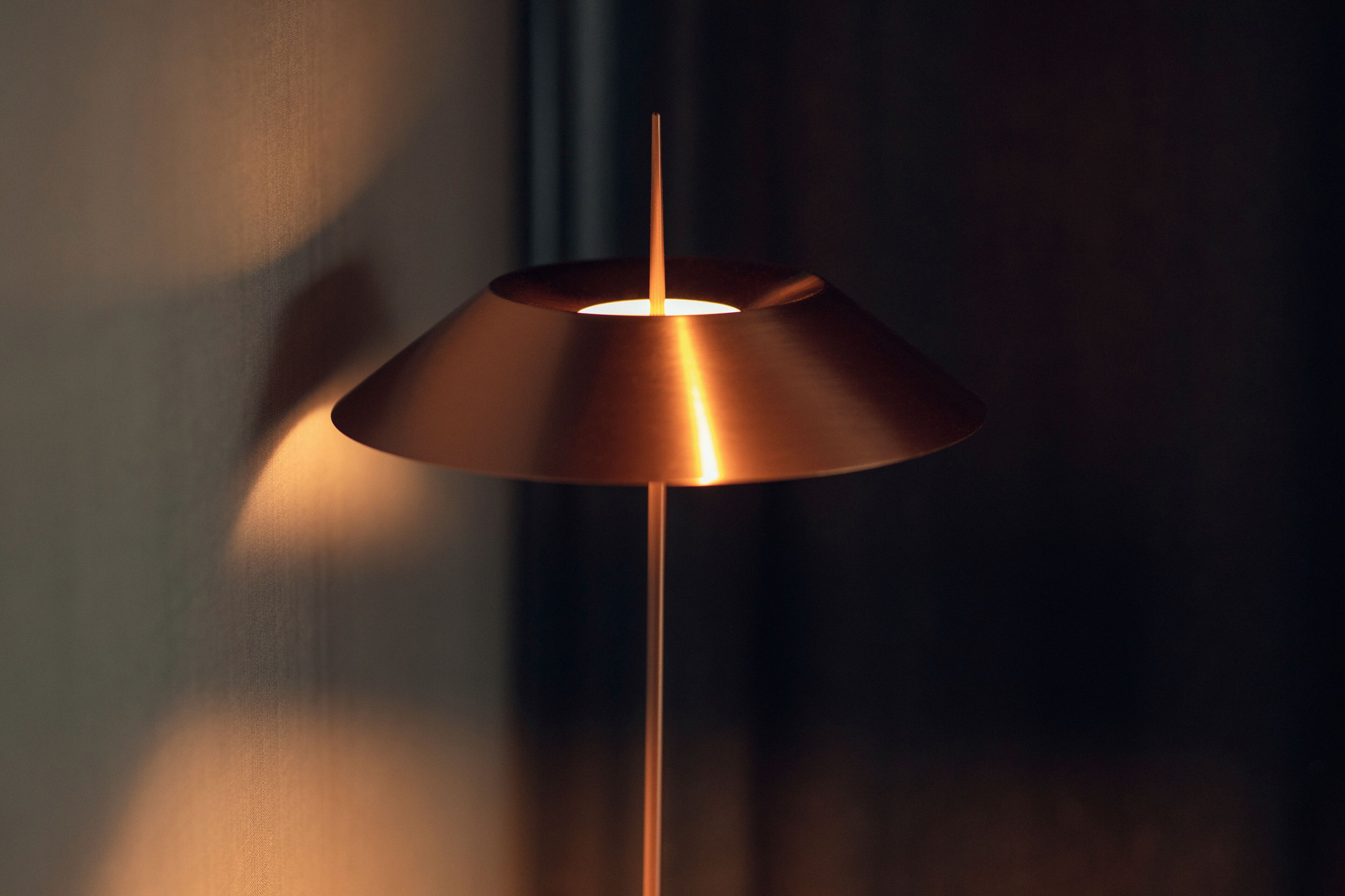 Une lampe moderne avec un revêtement métallique et une source de lumière centrale.