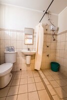 A bathroom with a toilet, sink, shower, and a sign instructing not to throw trash or paper towels in the toilet.