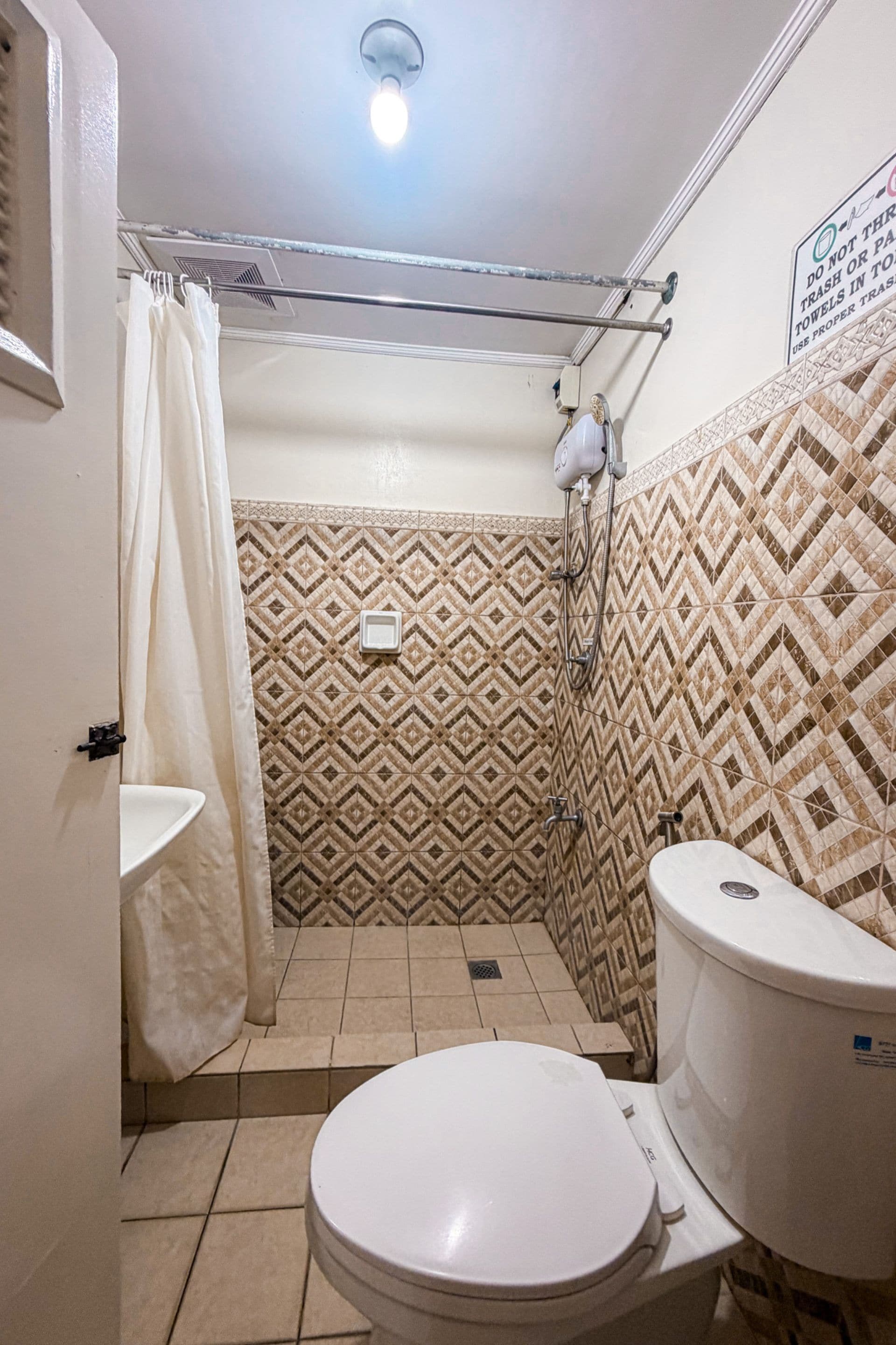 A small bathroom with a toilet, a shower, and a sink.