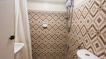 A small bathroom with a toilet, a shower, and a sink.