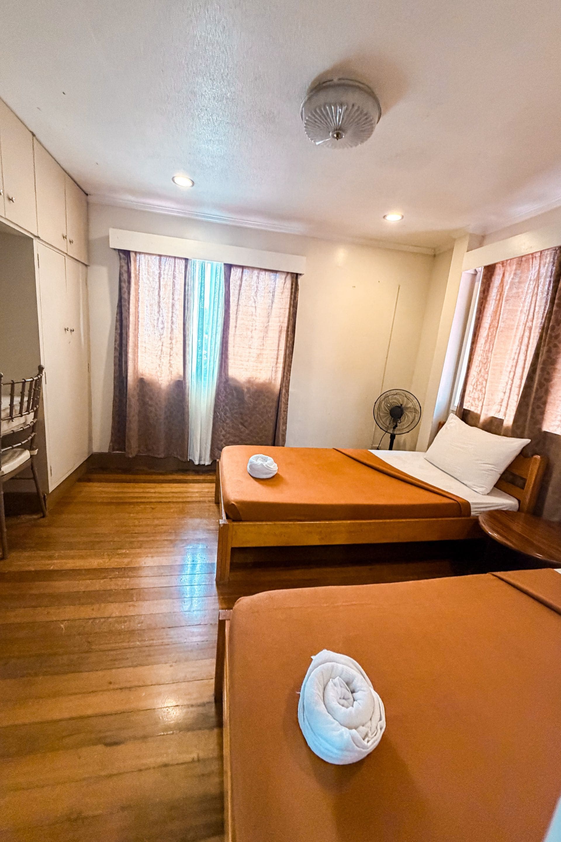A hotel room with two beds, a desk, and a chair.