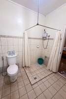 Un baño pequeño con inodoro, ducha y un cubo.