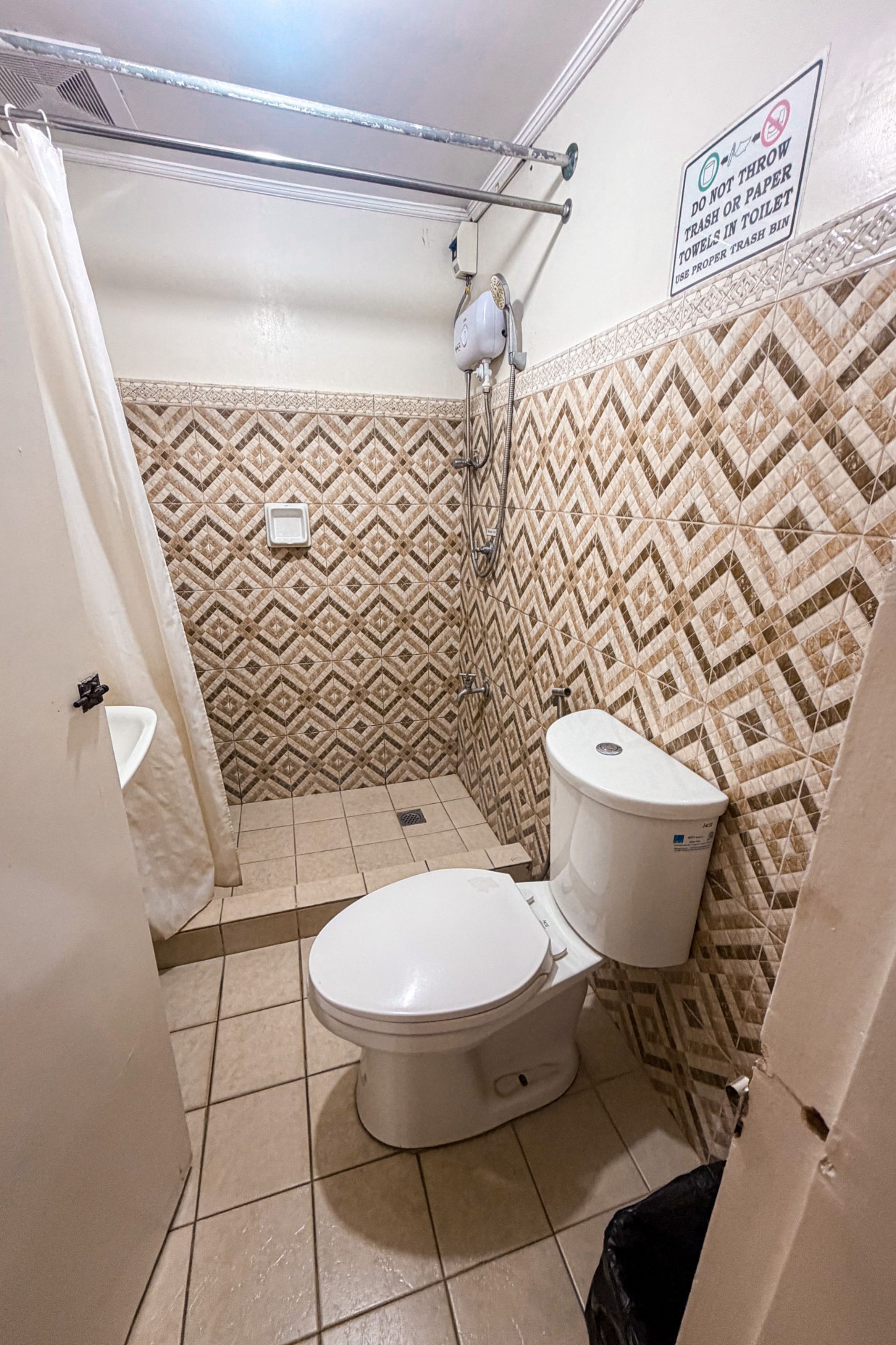 A bathroom with a toilet, shower, and a patterned wall.
