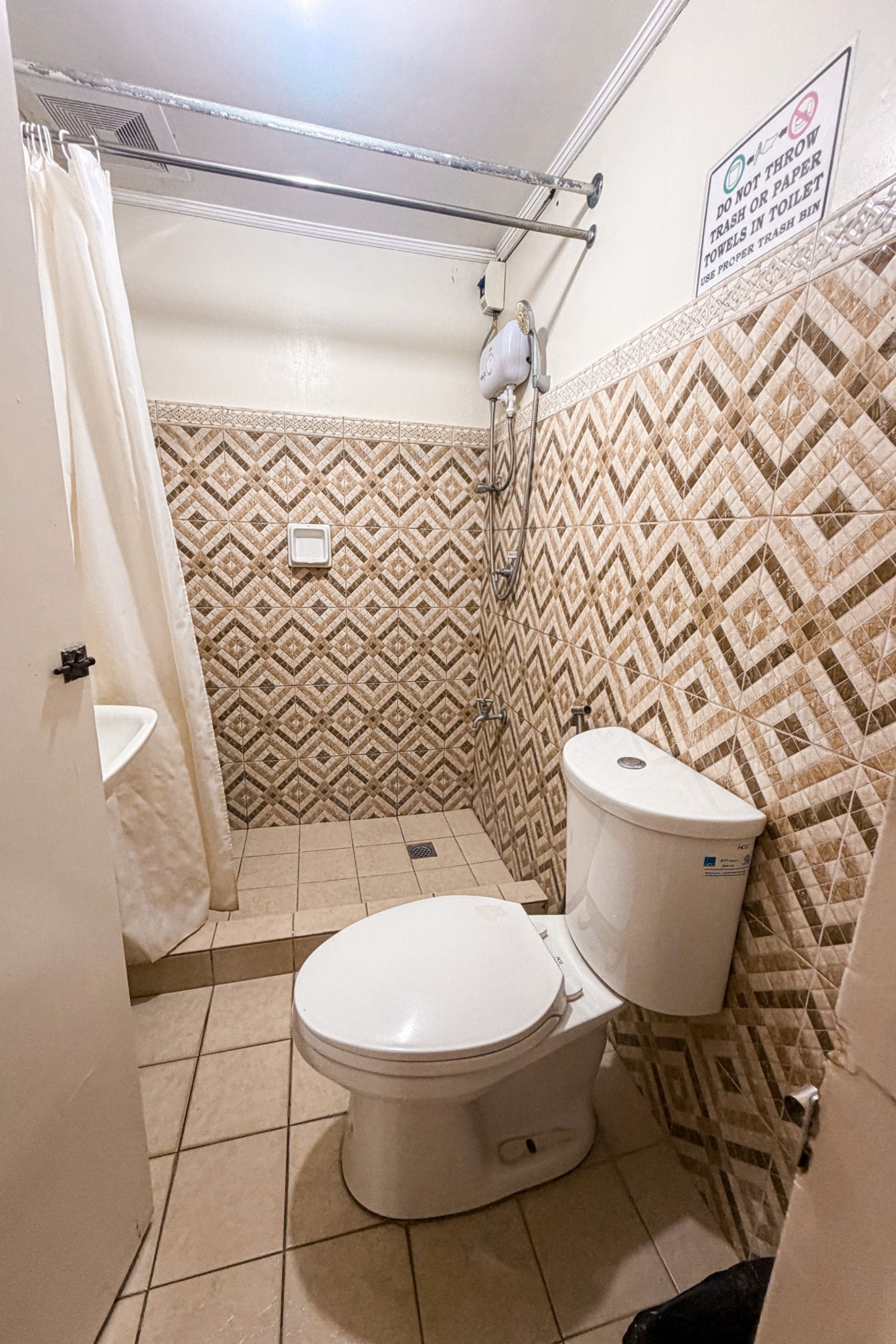 A small bathroom with a toilet, a shower, and a sink.
