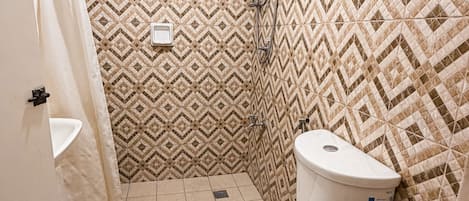 A small bathroom with a toilet, a shower, and a sink.