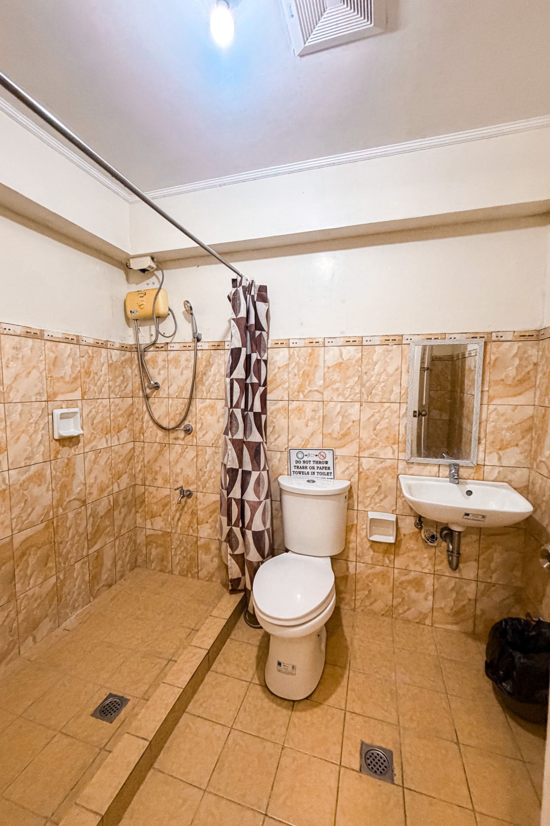 A bathroom with a shower, toilet, sink, and a sign prohibiting trash in the toilet.
