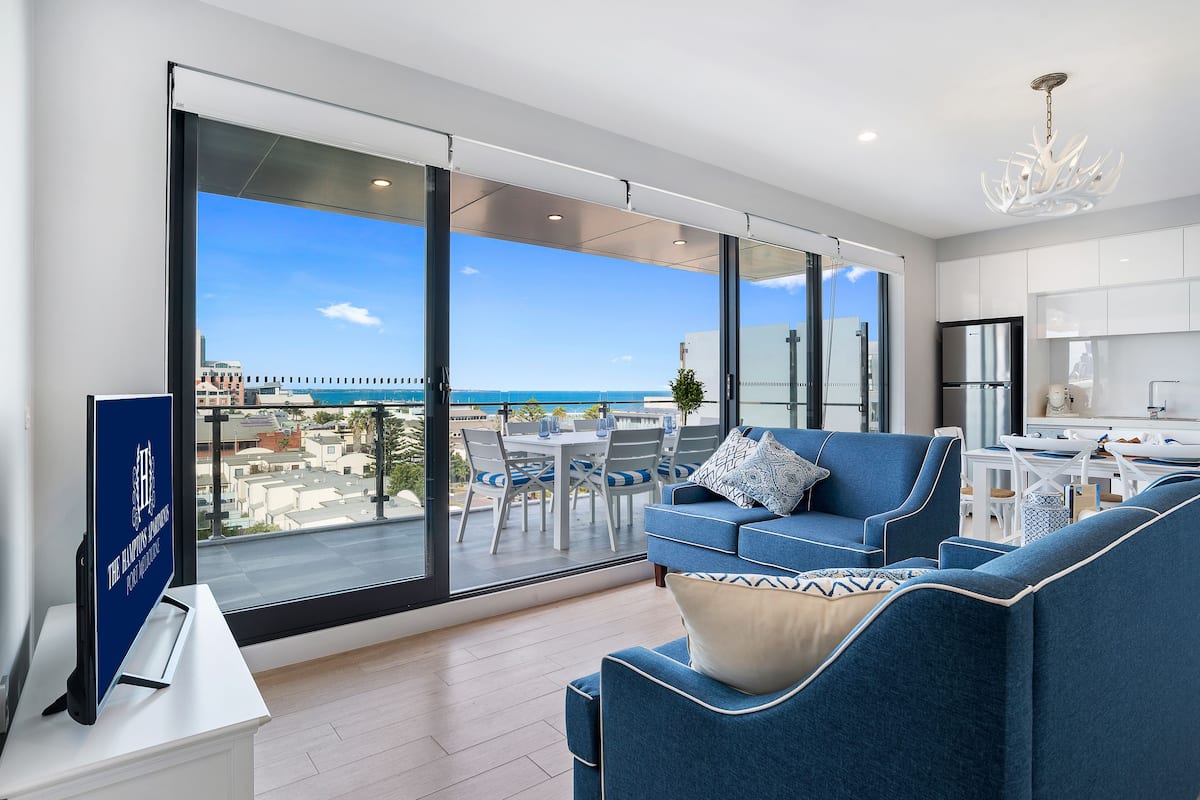 Un salon moderne avec un grand balcon, un coin repas et une cuisine.
