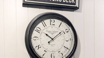 A wall-mounted clock with a sign above it reading "THE HAMPTONS DECK".