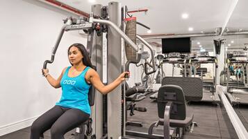 Ein Fitnessstudio mit verschiedenen Trainingsgeräten, darunter ein Kabelzuggerät und eine Beinpresse.