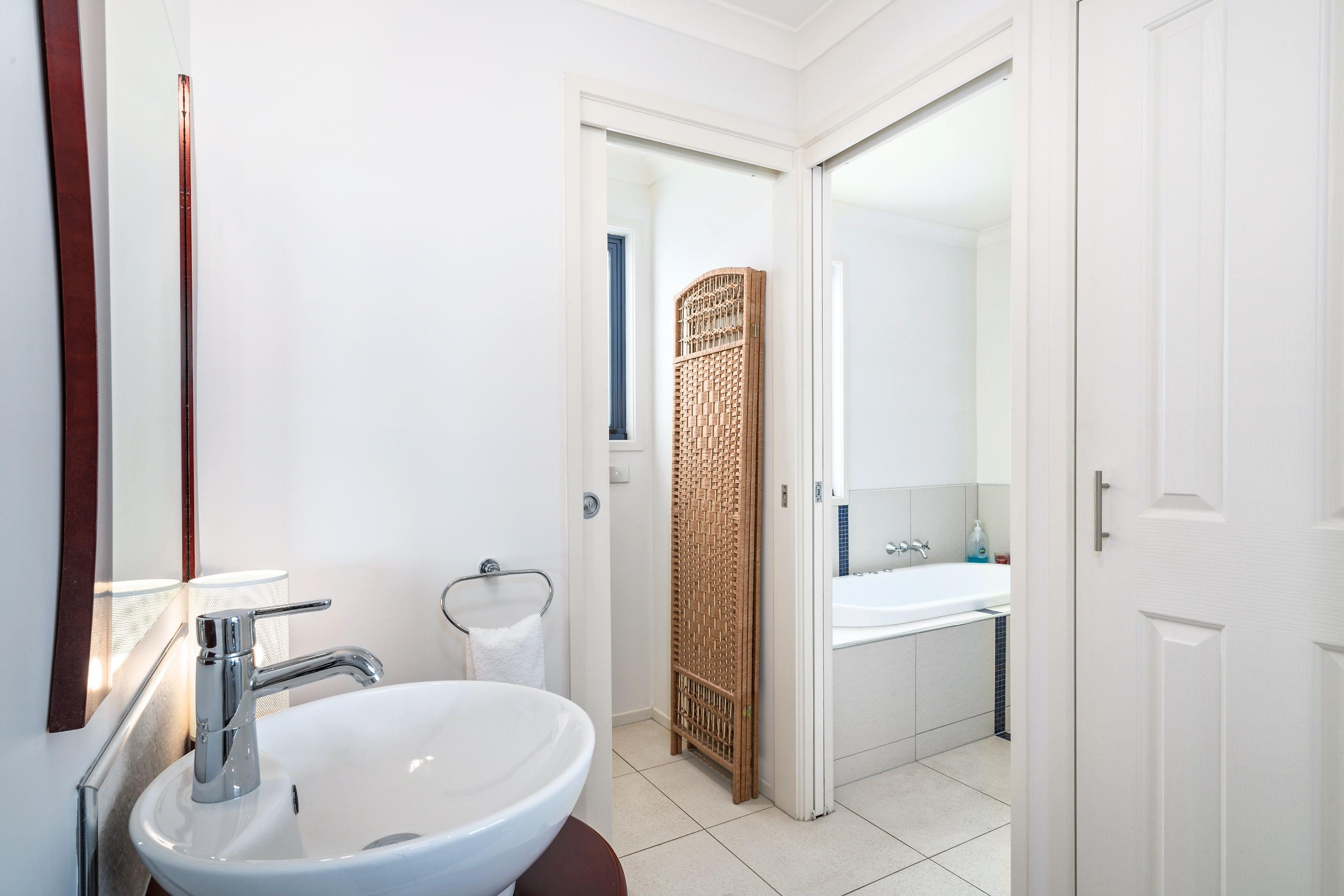 A modern bathroom with a white sink, chrome faucet, and a large mirror.