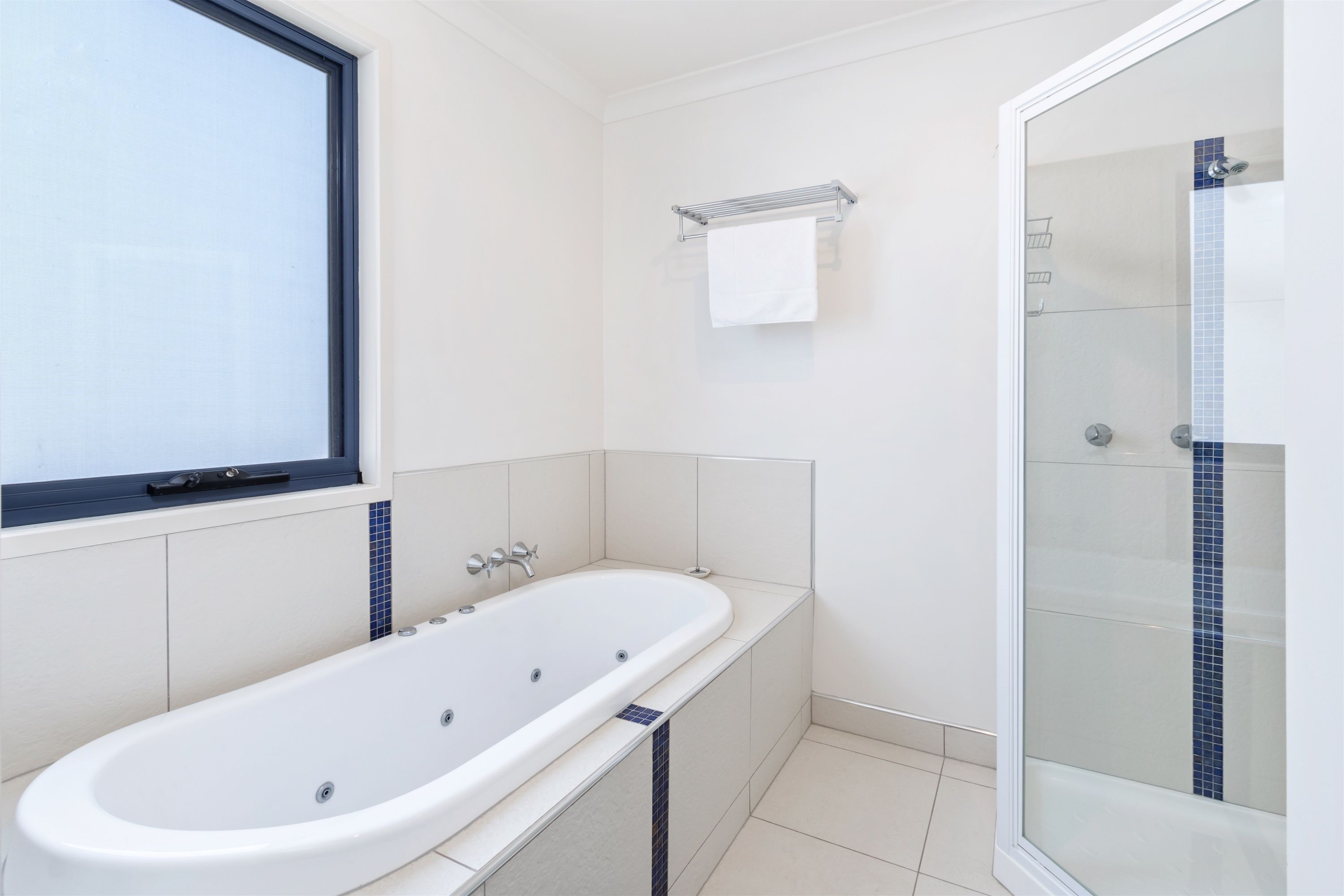Une salle de bain moderne avec une baignoire sur pieds, une douche à parois de verre et une fenêtre.