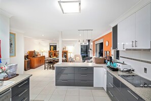 A modern kitchen with a central island, built-in appliances, and a dining area with a sofa and table. - Madsen Retreat (Penguin)