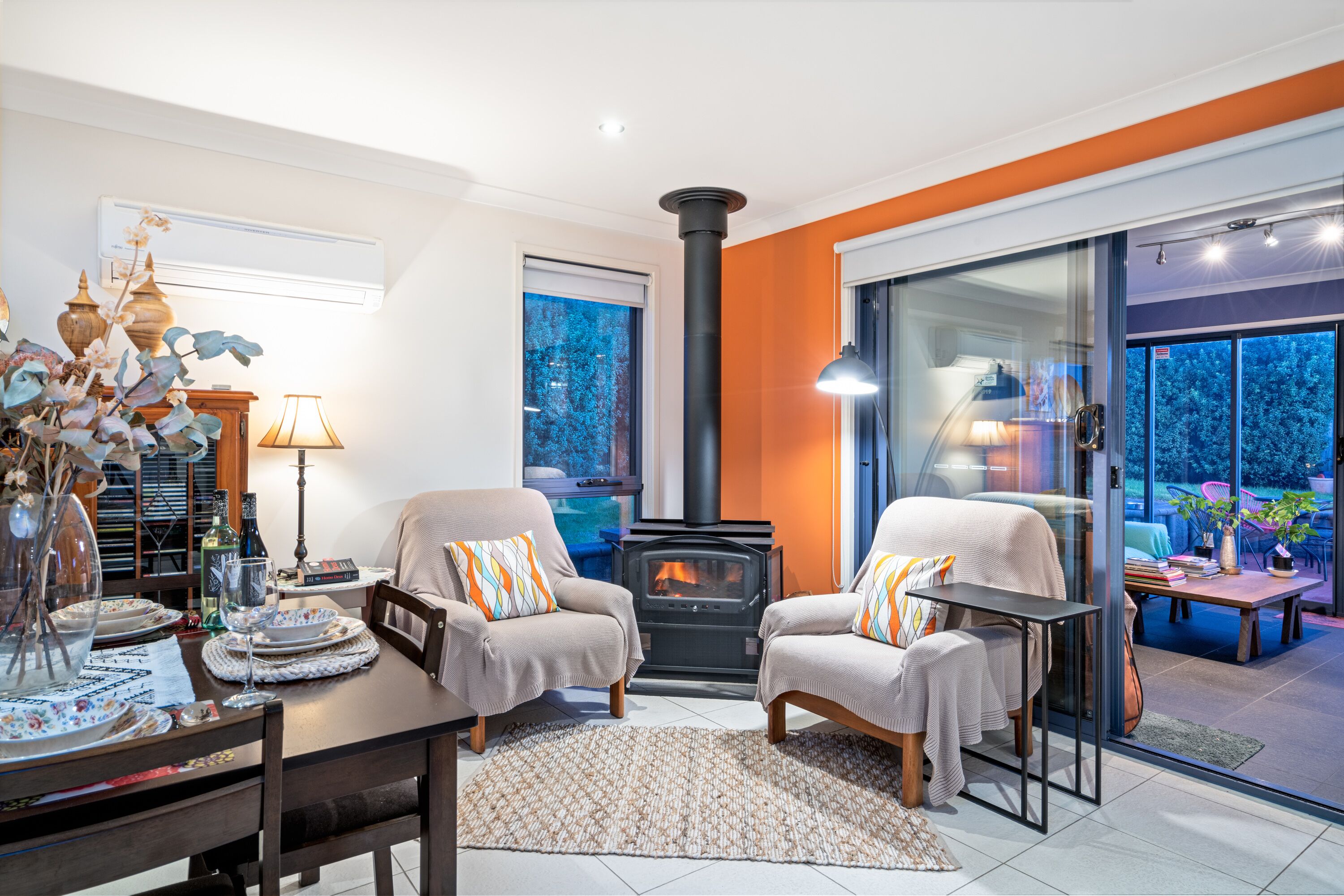 A cozy living room with two armchairs, a dining table, and a fireplace.